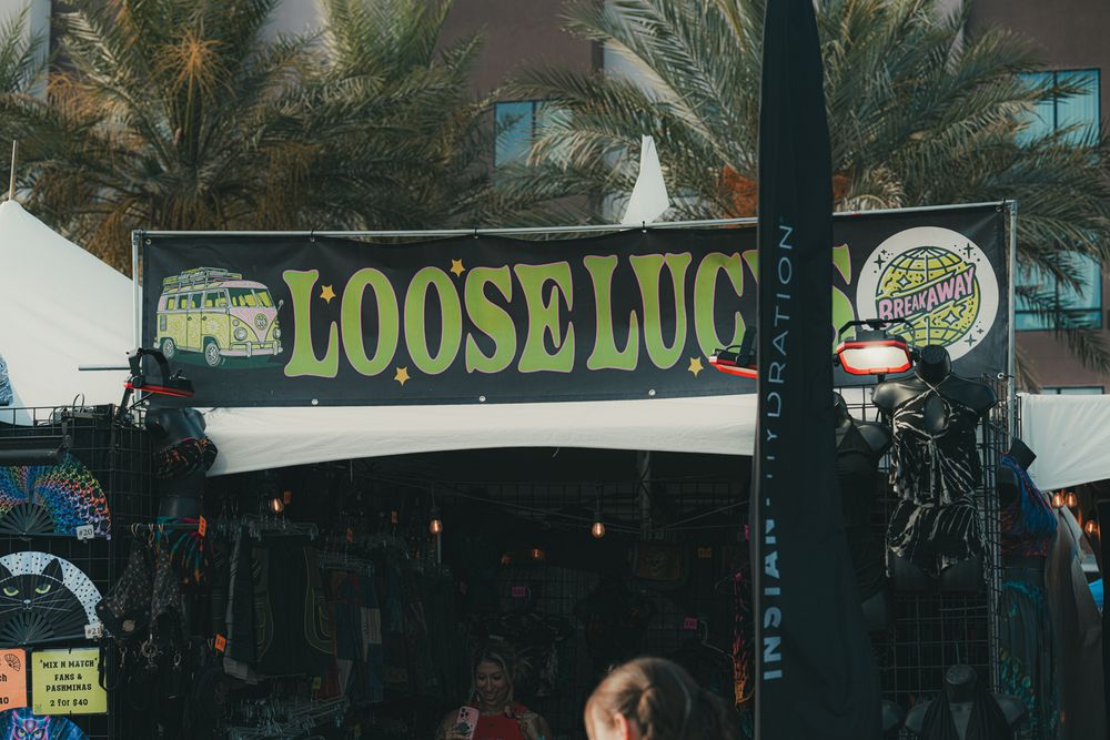 Loose Lucy bar sign with palm trees and festive decorations at an outdoor tropical venue.