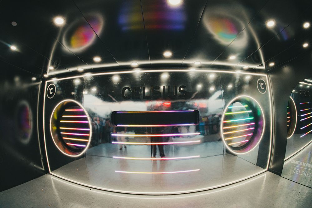 Futuristic DJ booth with colorful neon ring lights and glowing circular speakers in a dark entertainment venue.