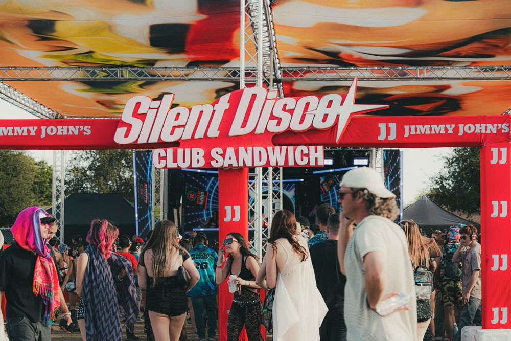 Crowd enjoying a Silent Disco Club Sandwich event sponsored by Jimmy John's at an outdoor music festival.