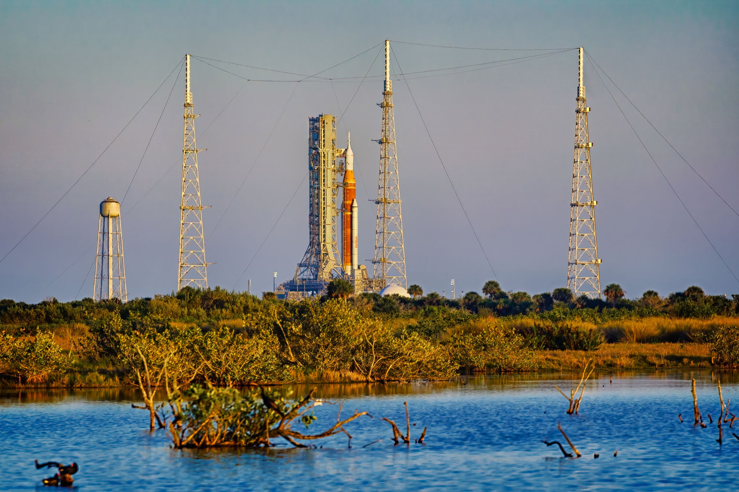 NASA's Artemis rocket on the launch pad at Kennedy Space Center with water in the foreground.