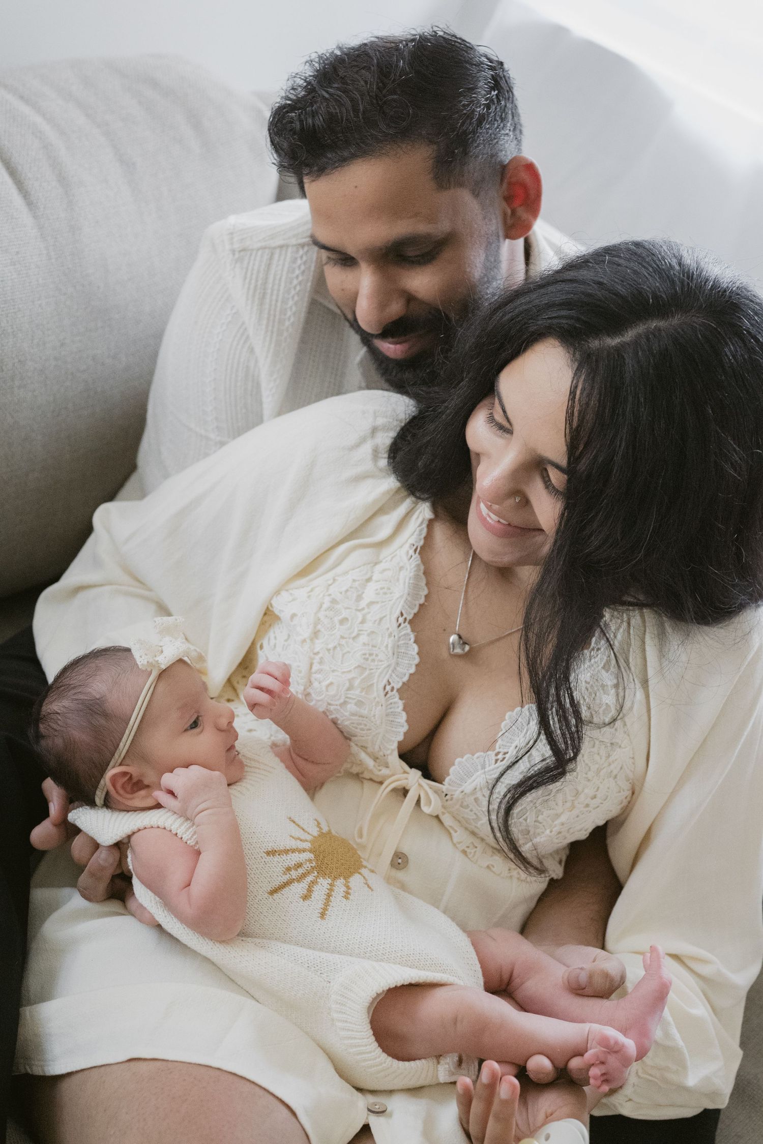 Mom smiling and holding her baby while Dad looks on from behind
