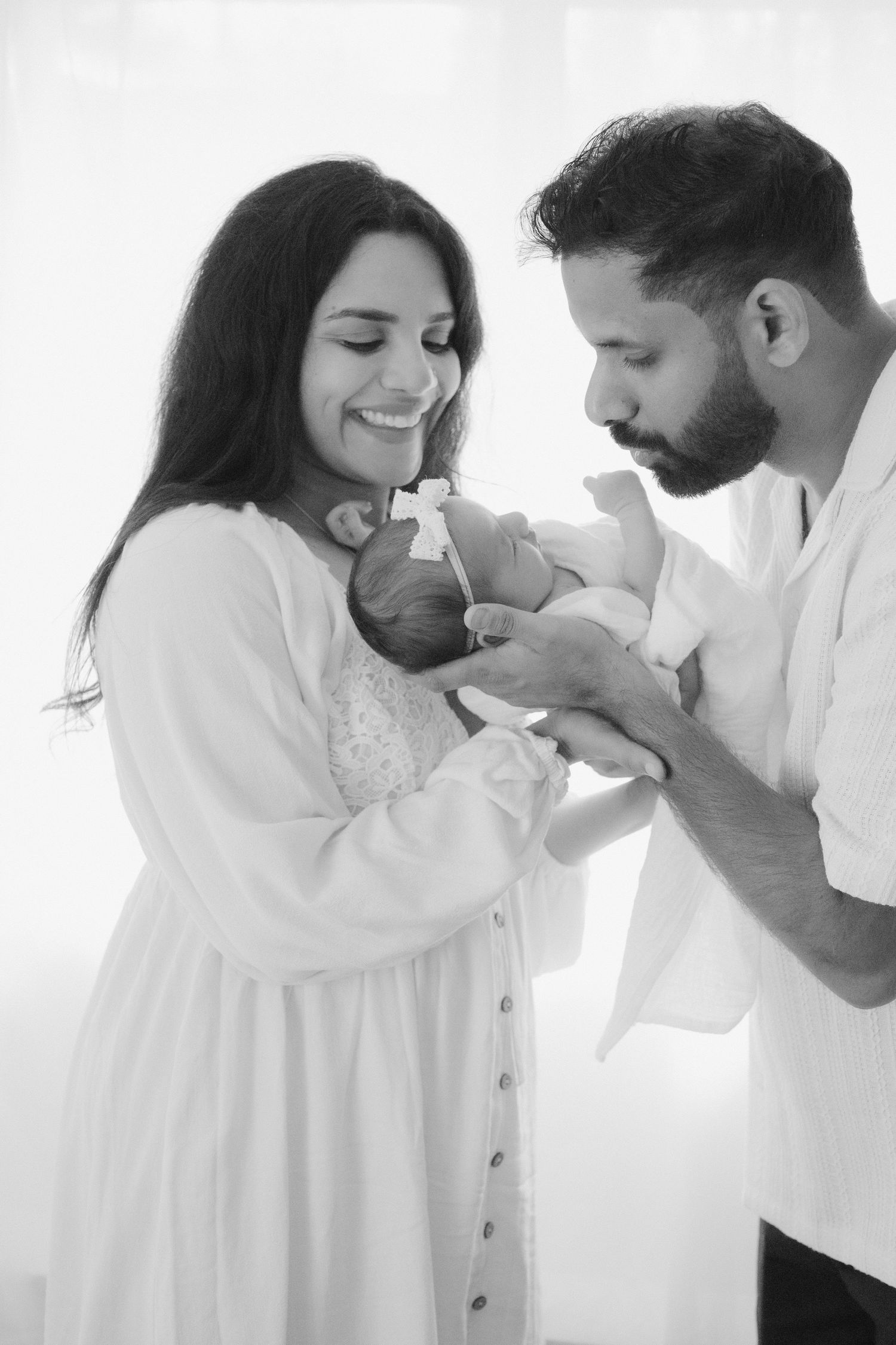 Parents smiling over sleeping newborn baby at home, newborn family photography North Vancouver