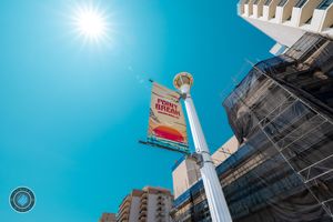 Low angle view of a Point Break sign on a pole against a bright blue sky with sunlight and urban buildings.