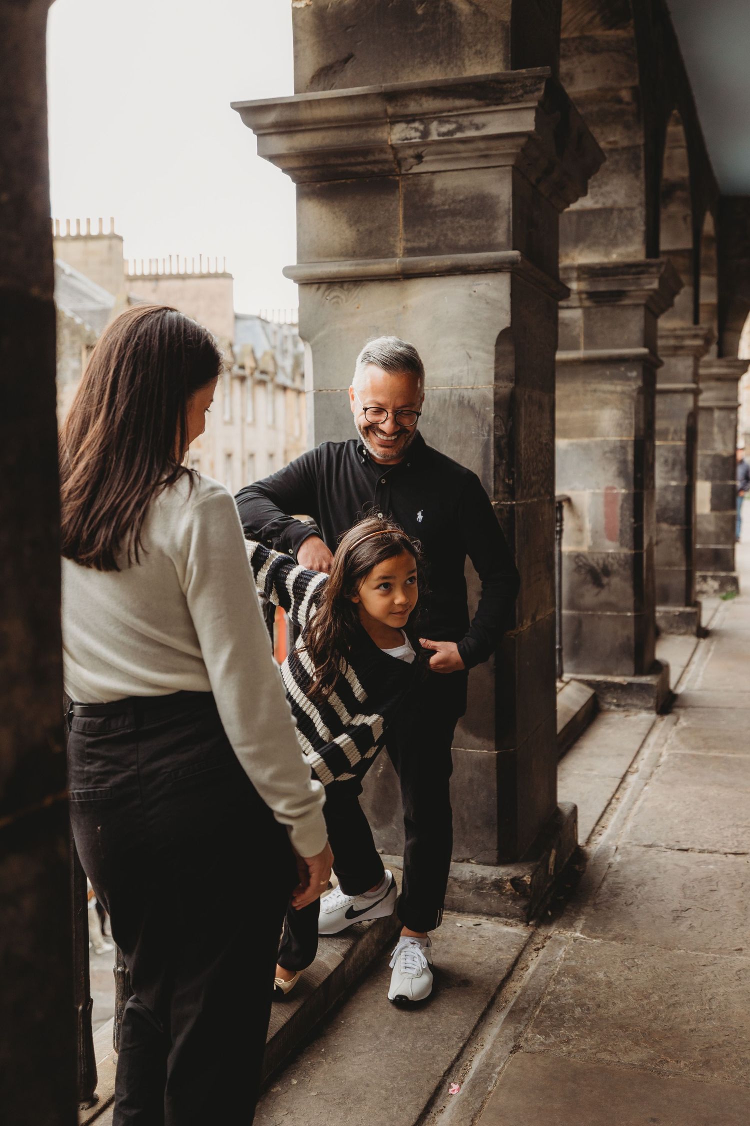 Family walking together on a historic European street with stone architecture in the background.