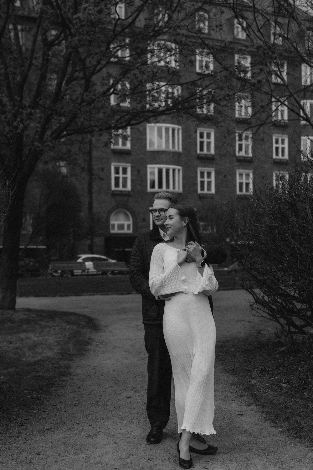 Black and white engagement portrait of a couple standing together in Helsinki city centre