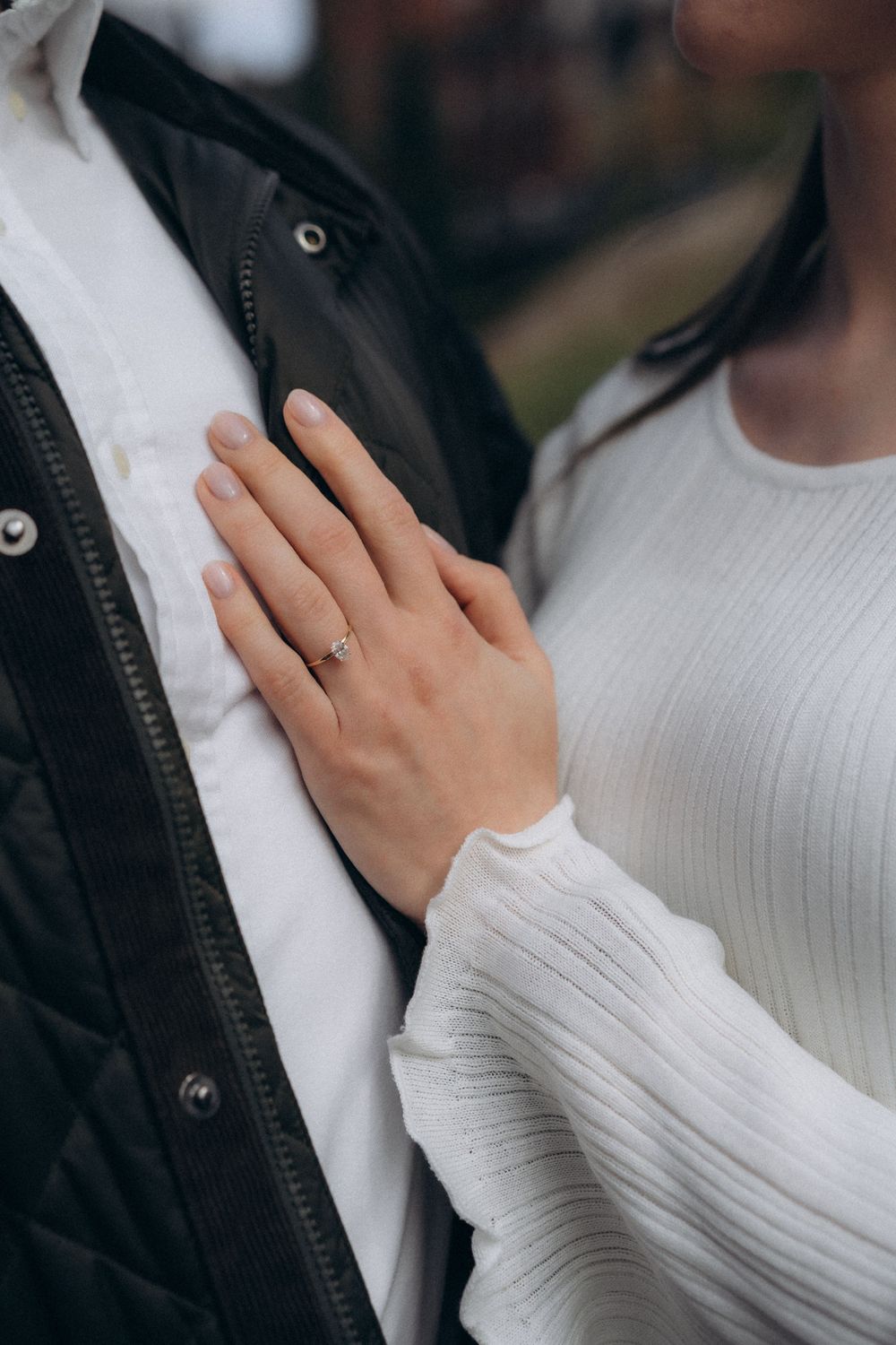 Close-up engagement photo of a bride resting her hand on her partner’s chest during an engagement photoshoot