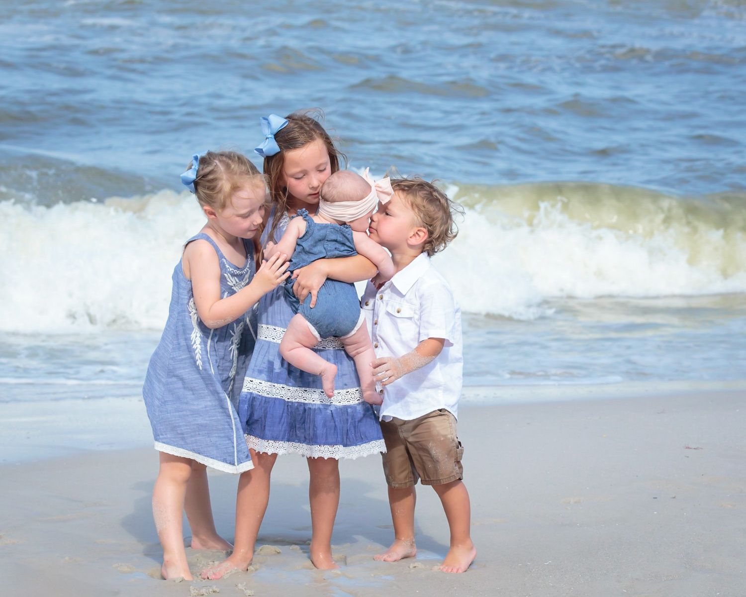 Children playing and hugging together by the ocean waves on a sunny beach day by Naples FL photographer, Mark Block