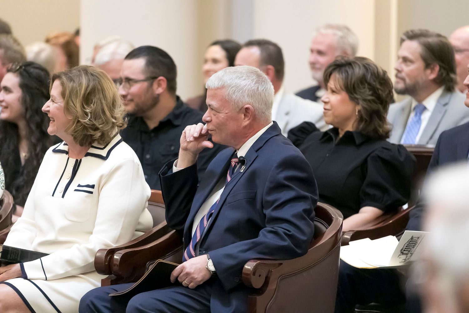 Business professionals seated in rows at a conference or seminar listening attentively to a presentation.
