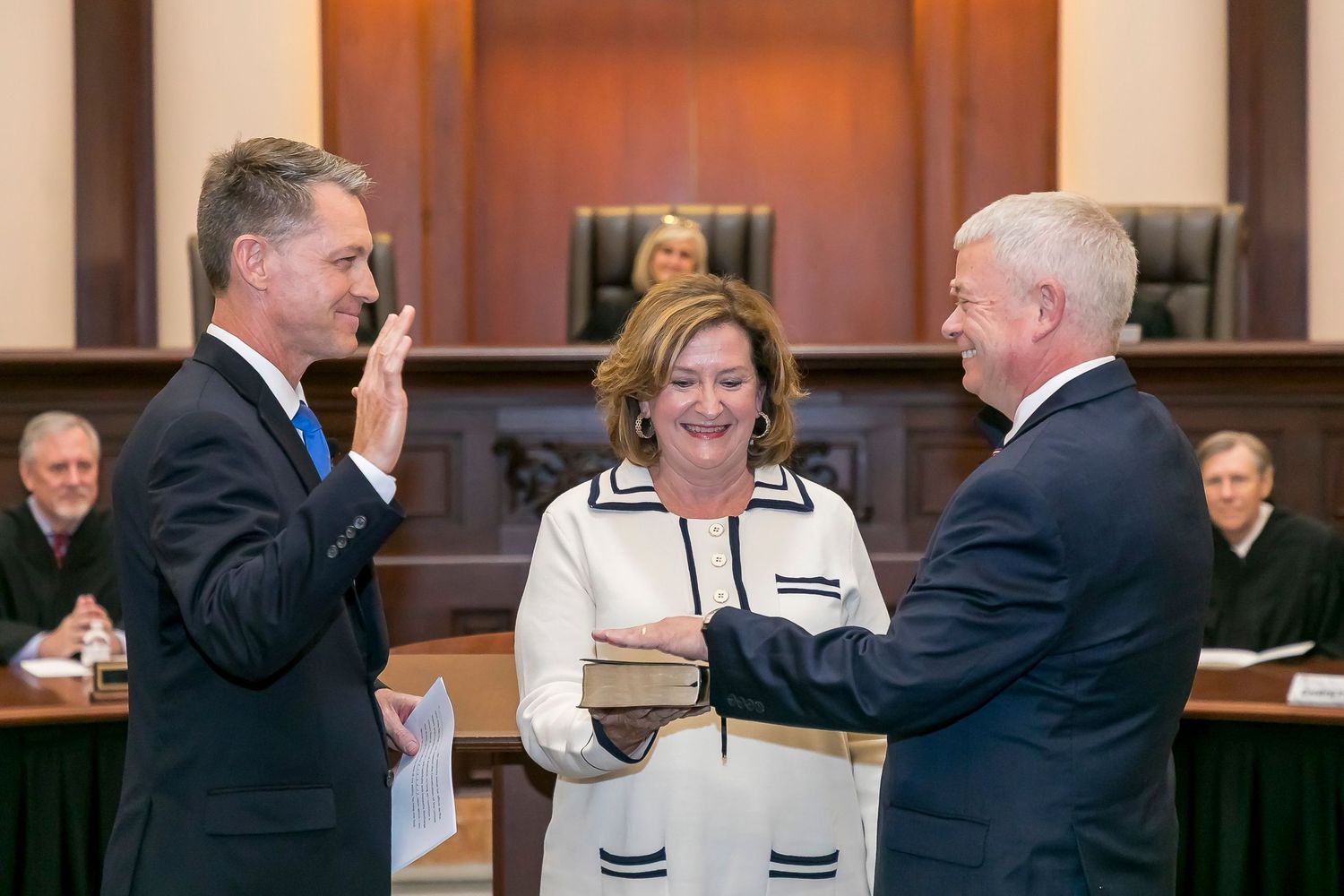 A judge administers an oath to a person in a formal courtroom setting during a swearing-in ceremony.