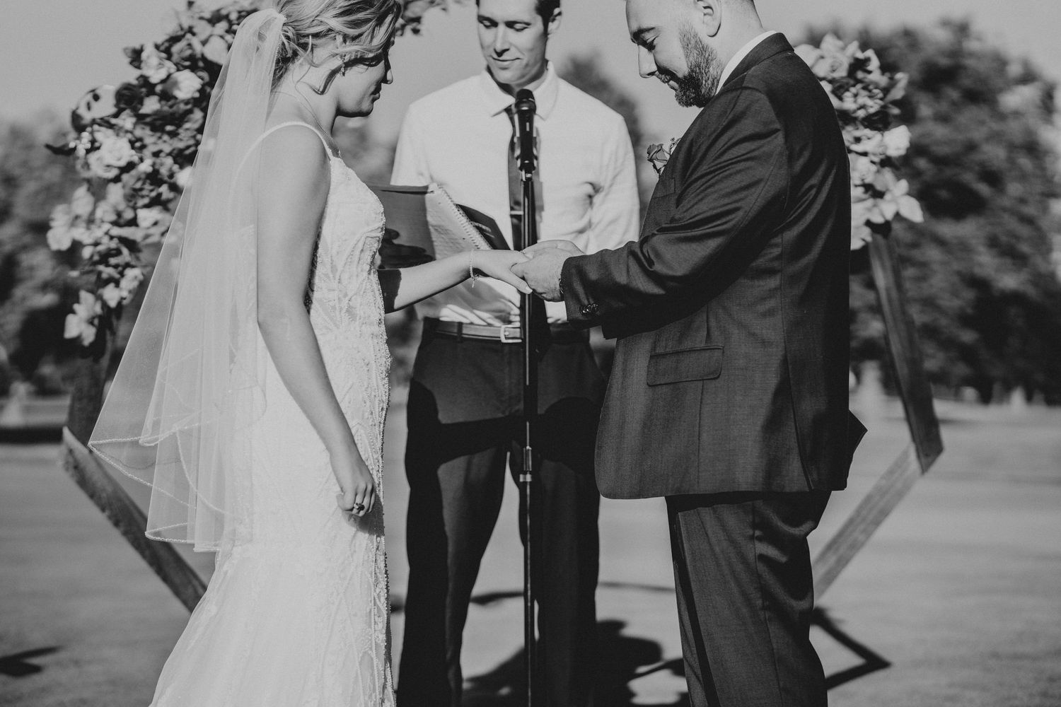 Black and white photo of a wedding ceremony taking place outdoors with guests watching.