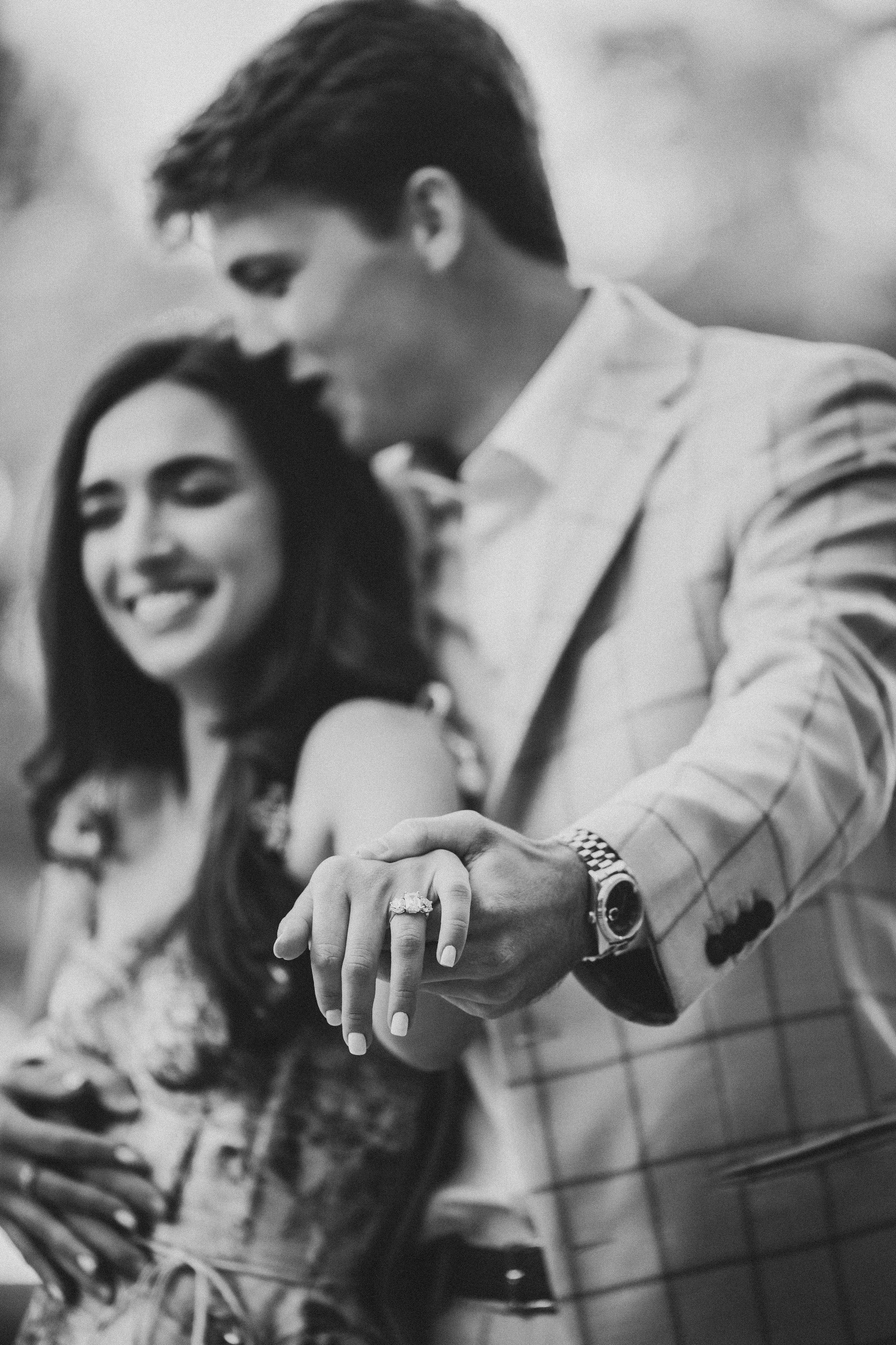 Detail shot of hands with engagement ring, fountain softly blurred in background