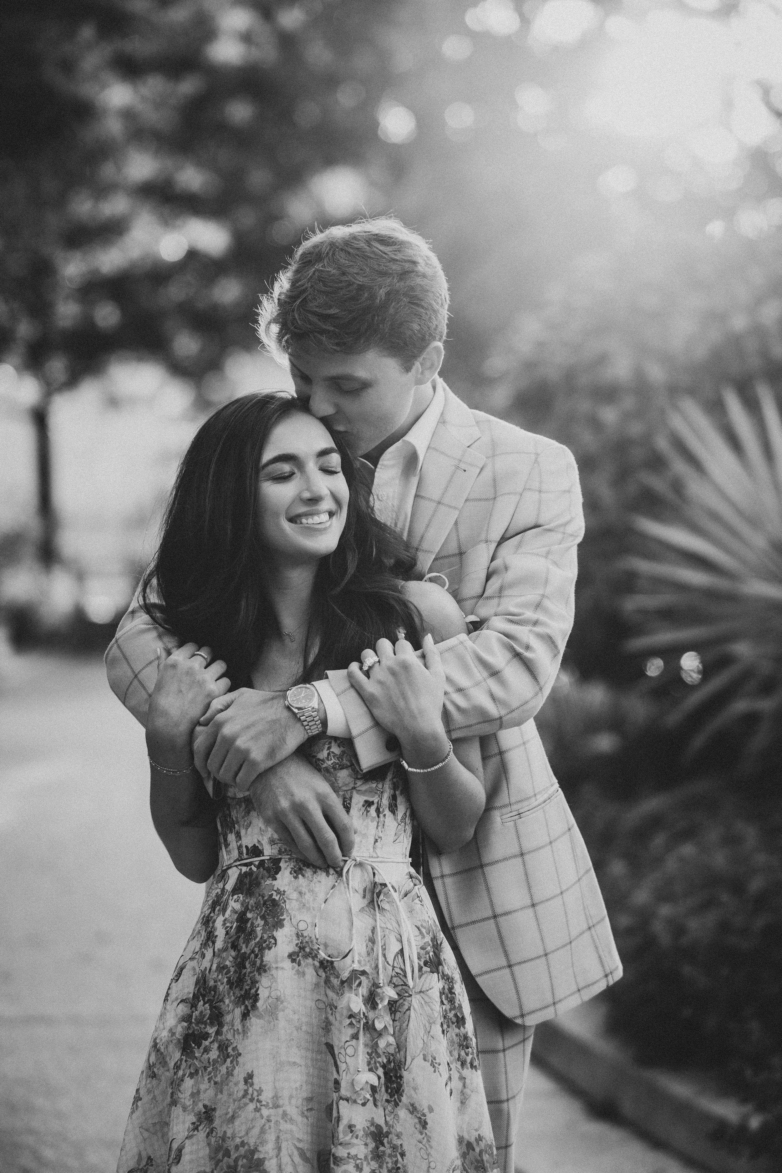 A romantic black and white photo sequence of a couple laughing and embracing in a garden setting.