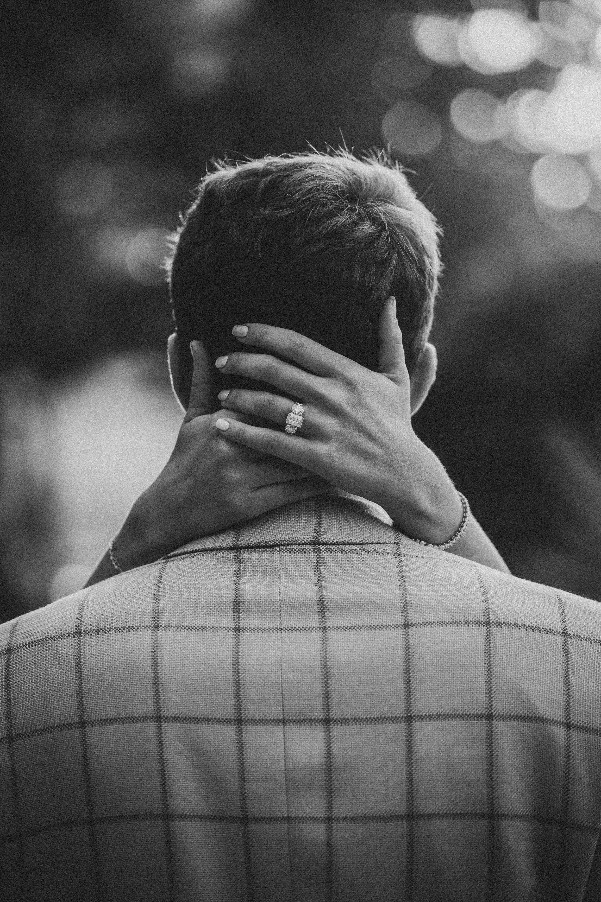 Detail shot of hands with engagement ring, fountain softly blurred in background