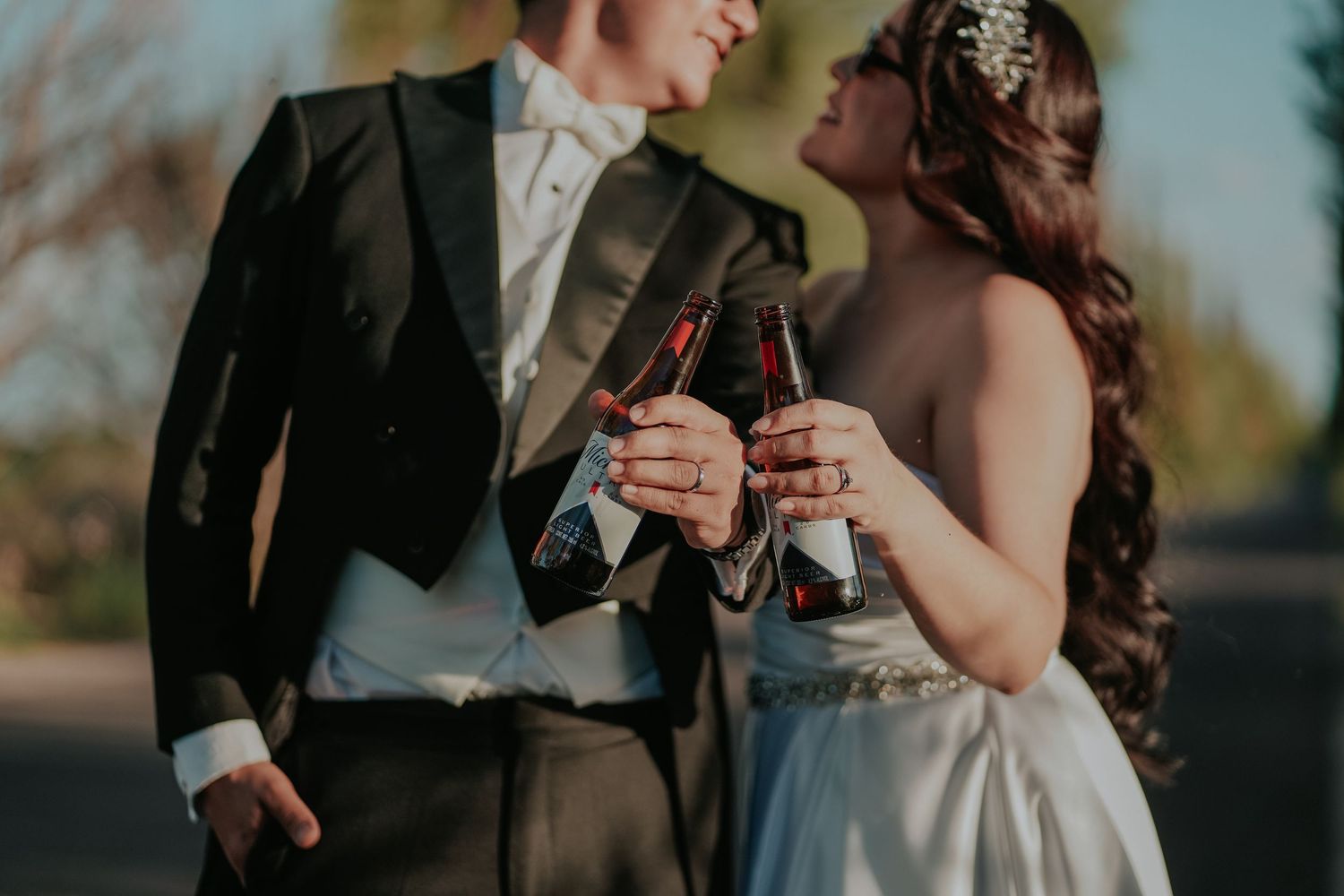 A couple in formal wedding attire embraces outdoors during a sunset photo session.