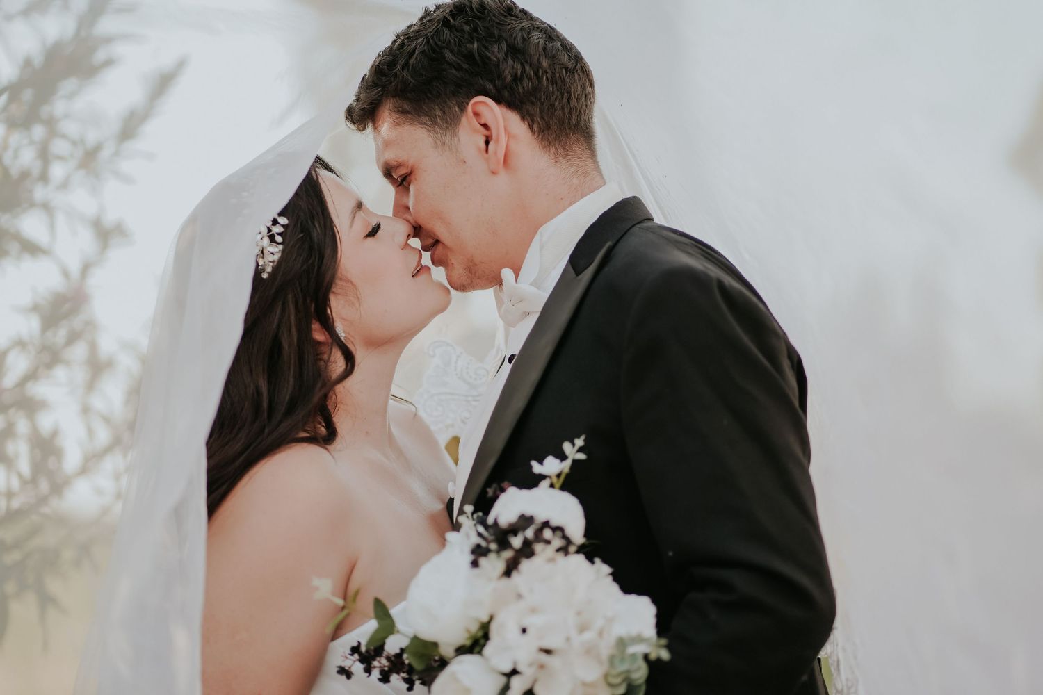 A romantic wedding couple shares intimate moments in a series of black and white portraits with soft lighting.