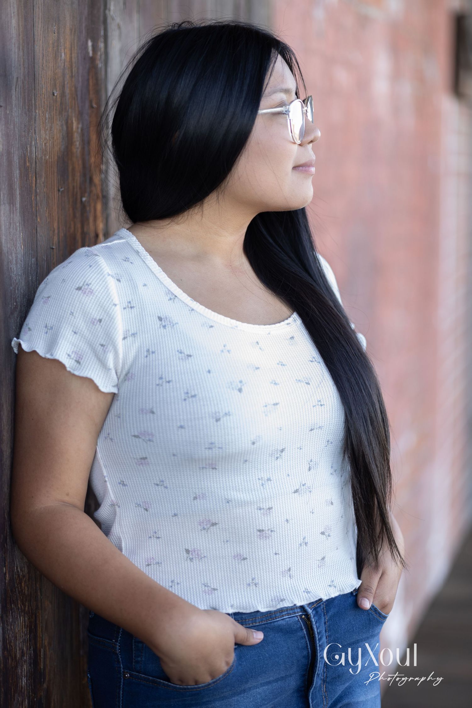 Side profile portrait against wall showing person in white top with long dark hair.