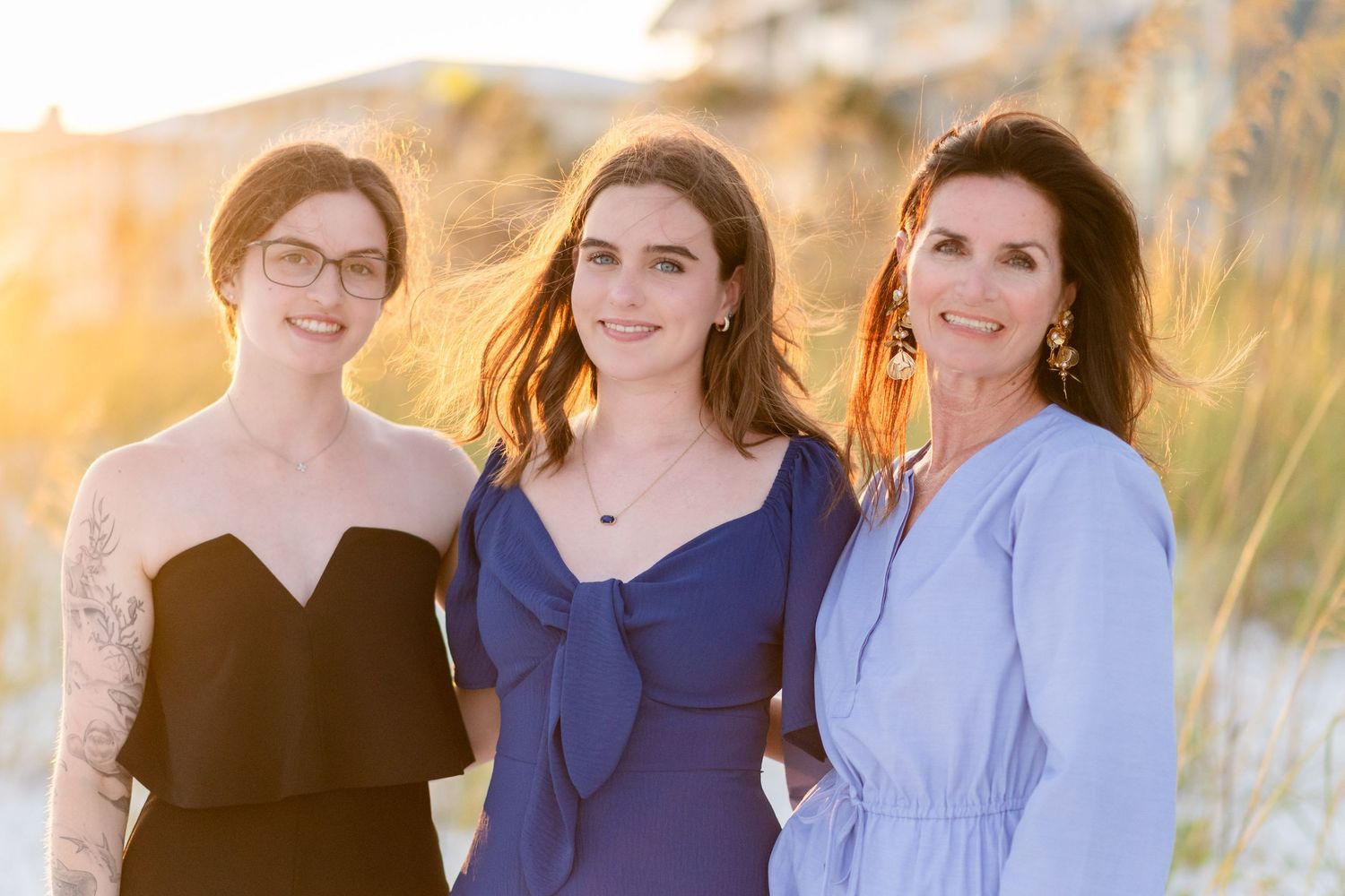 A family poses together in a field at sunset wearing coordinated navy blue and black outfits.