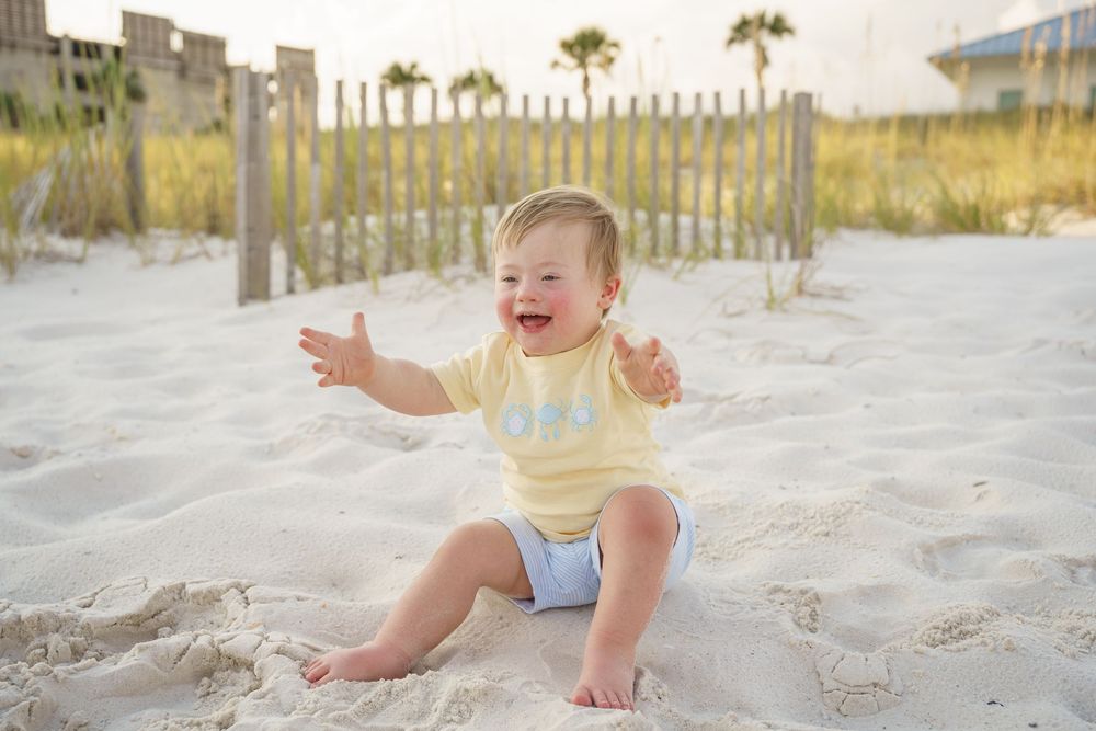 A joyful moment captured on a sunny beach with white sand and wooden fencing in the background.