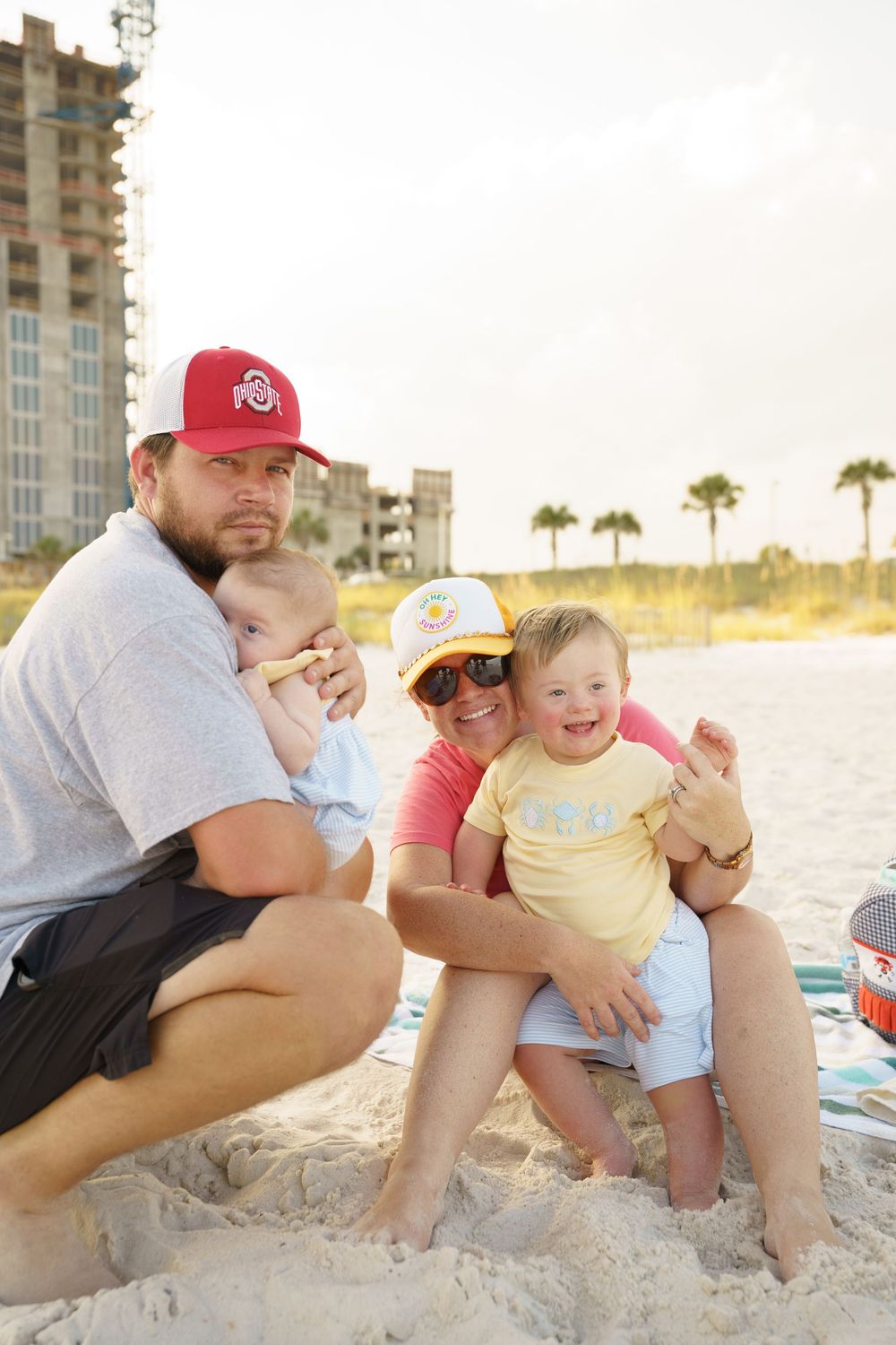Family enjoying a relaxing afternoon together on a sandy beach with high-rise buildings in the background.