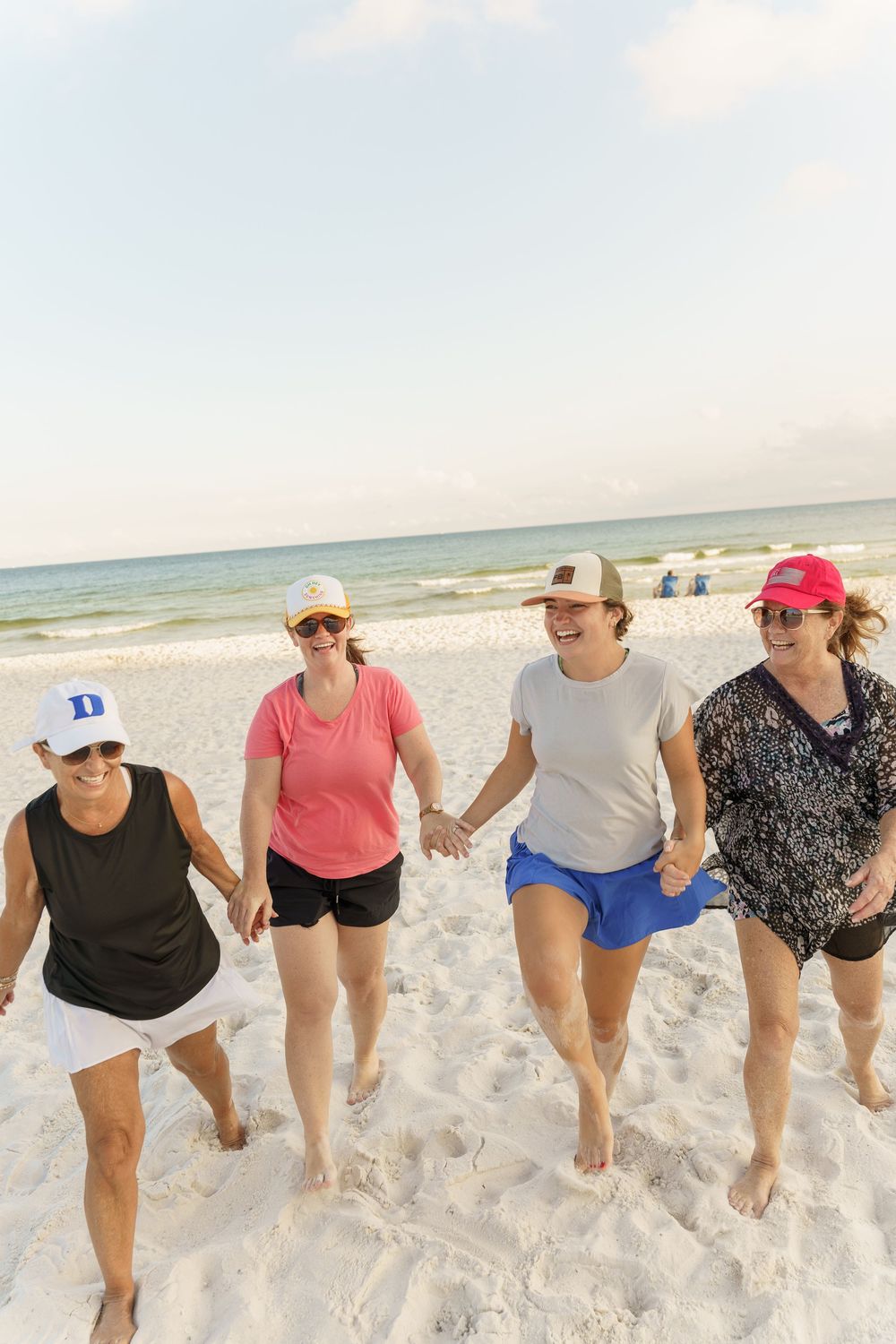 Line of people walking in synchronized formation along pristine white sand beach near ocean.