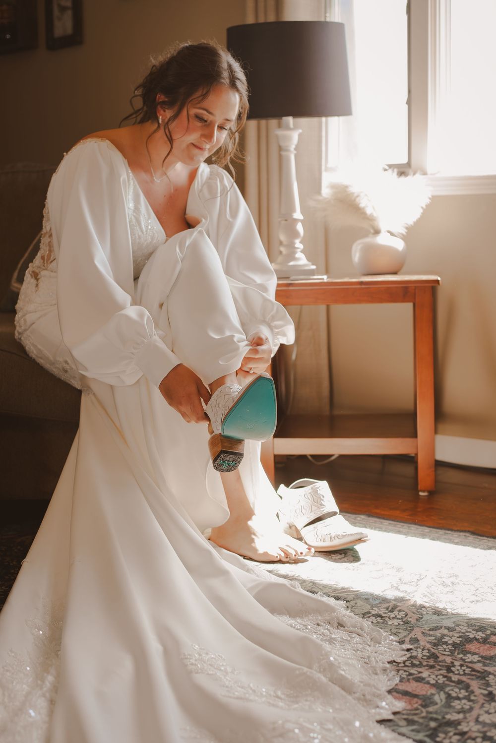 Getting ready scene with white wedding dress and morning light streaming through windows.