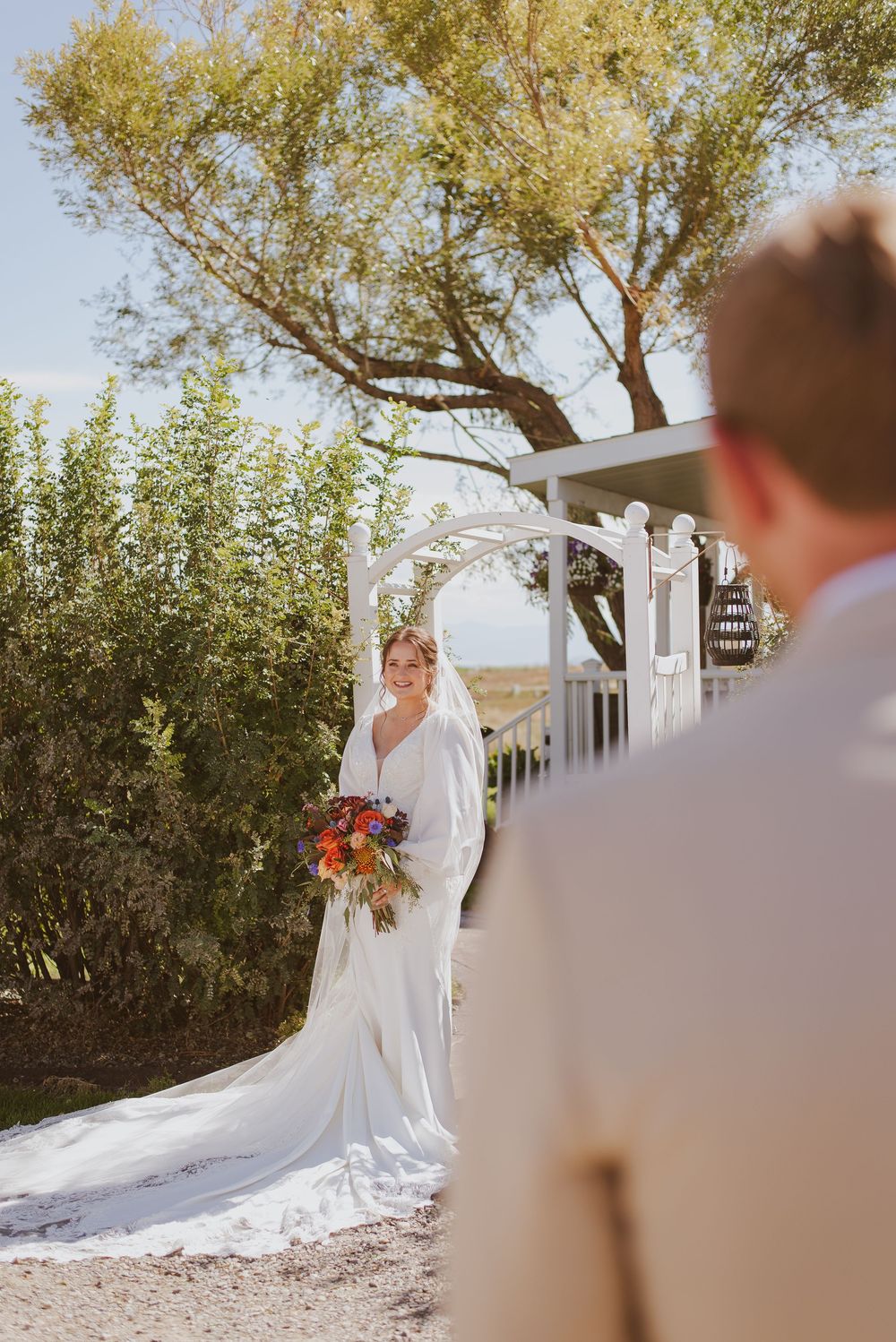Wedding photography sequence showing bride in flowing gown posing near trees and white architecture.