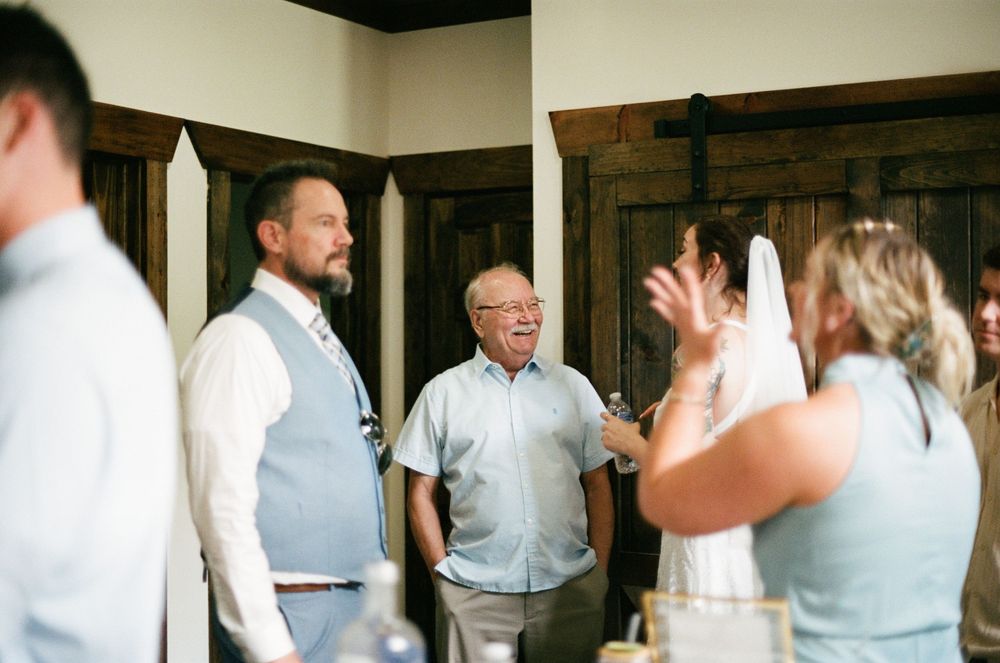 Guests laughing and socializing at an indoor wedding reception near rustic barn doors.