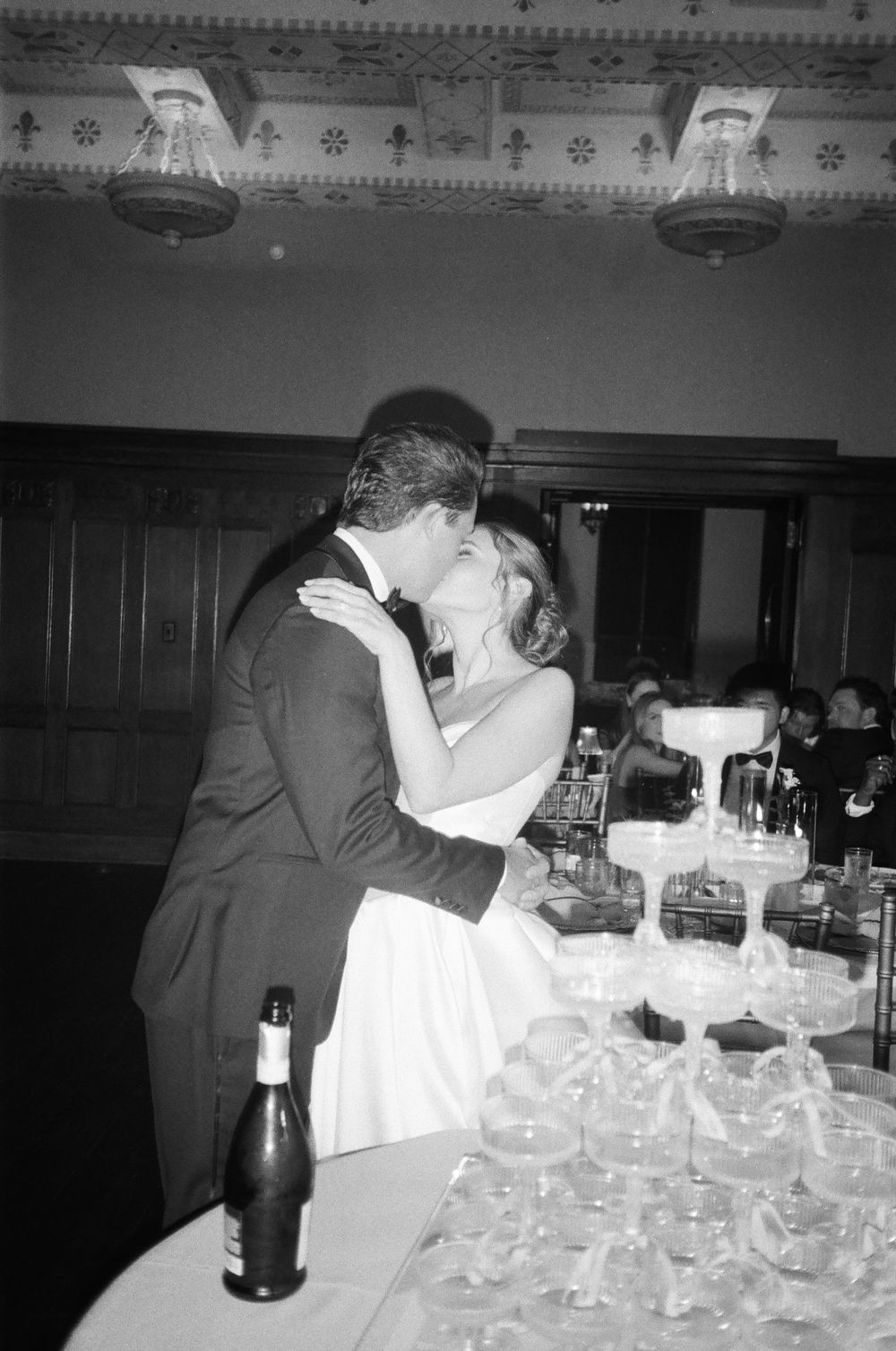 Black and white photograph showing multiple wine glasses arranged on a table at what appears to be a formal event.