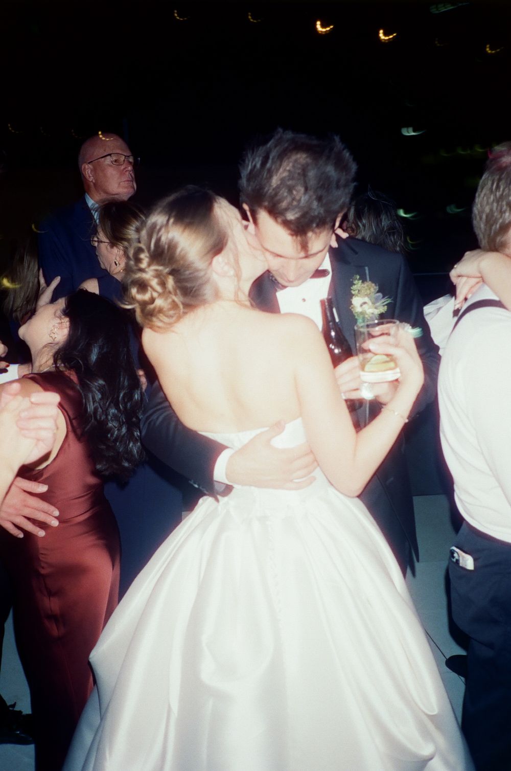 A couple shares an intimate dance at a wedding reception, with the bride wearing a classic white ballgown dress.