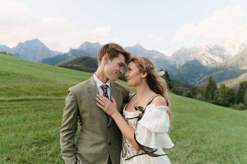 A romantic moment unfolds against a backdrop of snow-capped mountains and rolling green hills.