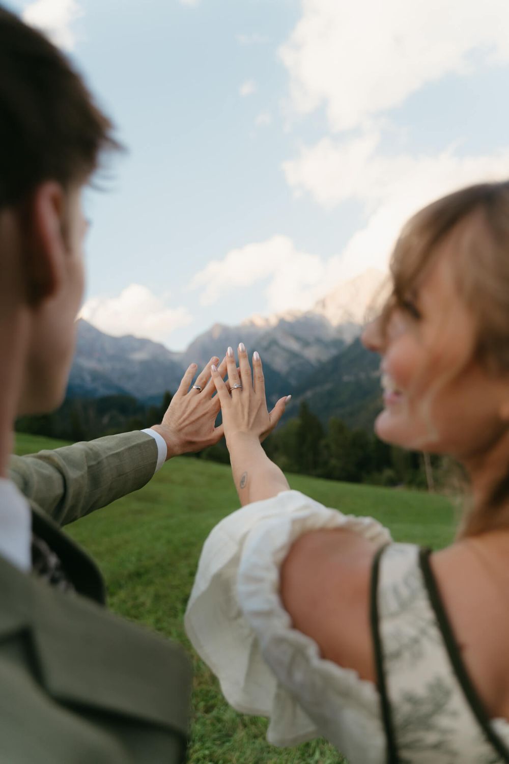 A series of five images showing two people high-fiving with mountains and green fields in the background.
