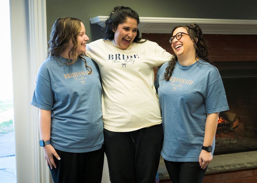 Group wearing matching blue and white t-shirts share a candid moment together indoors.