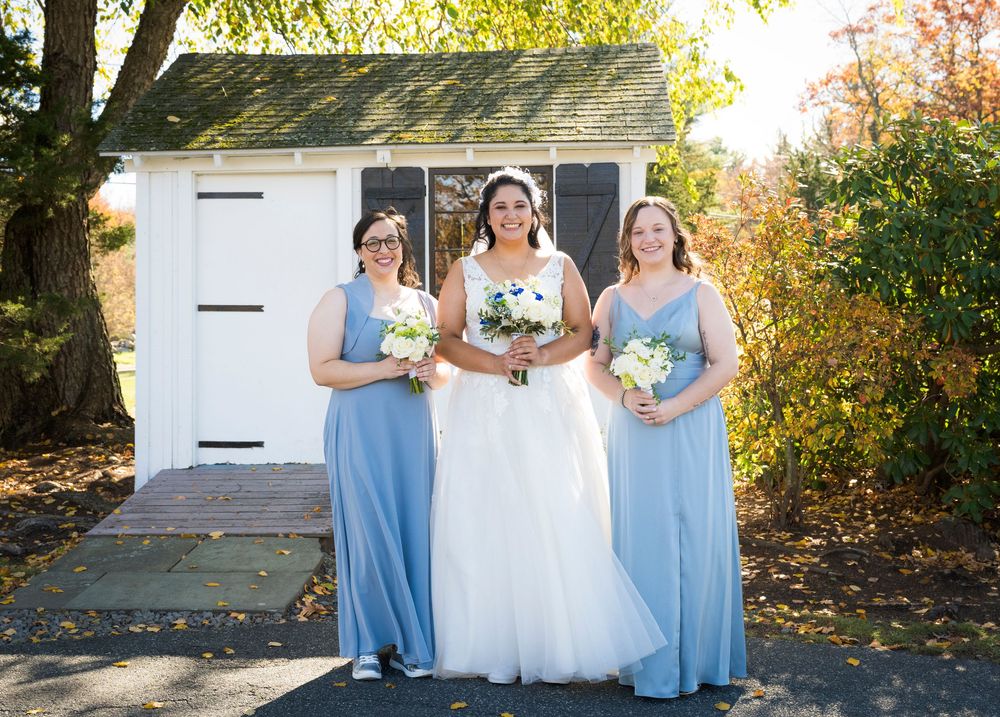 Wedding party in light blue bridesmaid dresses and white gown pose together on stone steps during autumn.
