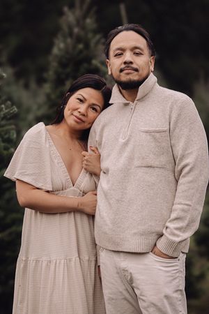 A couple in coordinating cream-colored outfits embrace lovingly in a romantic outdoor photoshoot series.
