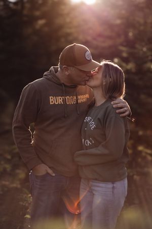 A romantic couple sharing an intimate moment at sunset with warm backlighting creating a dreamy atmosphere.