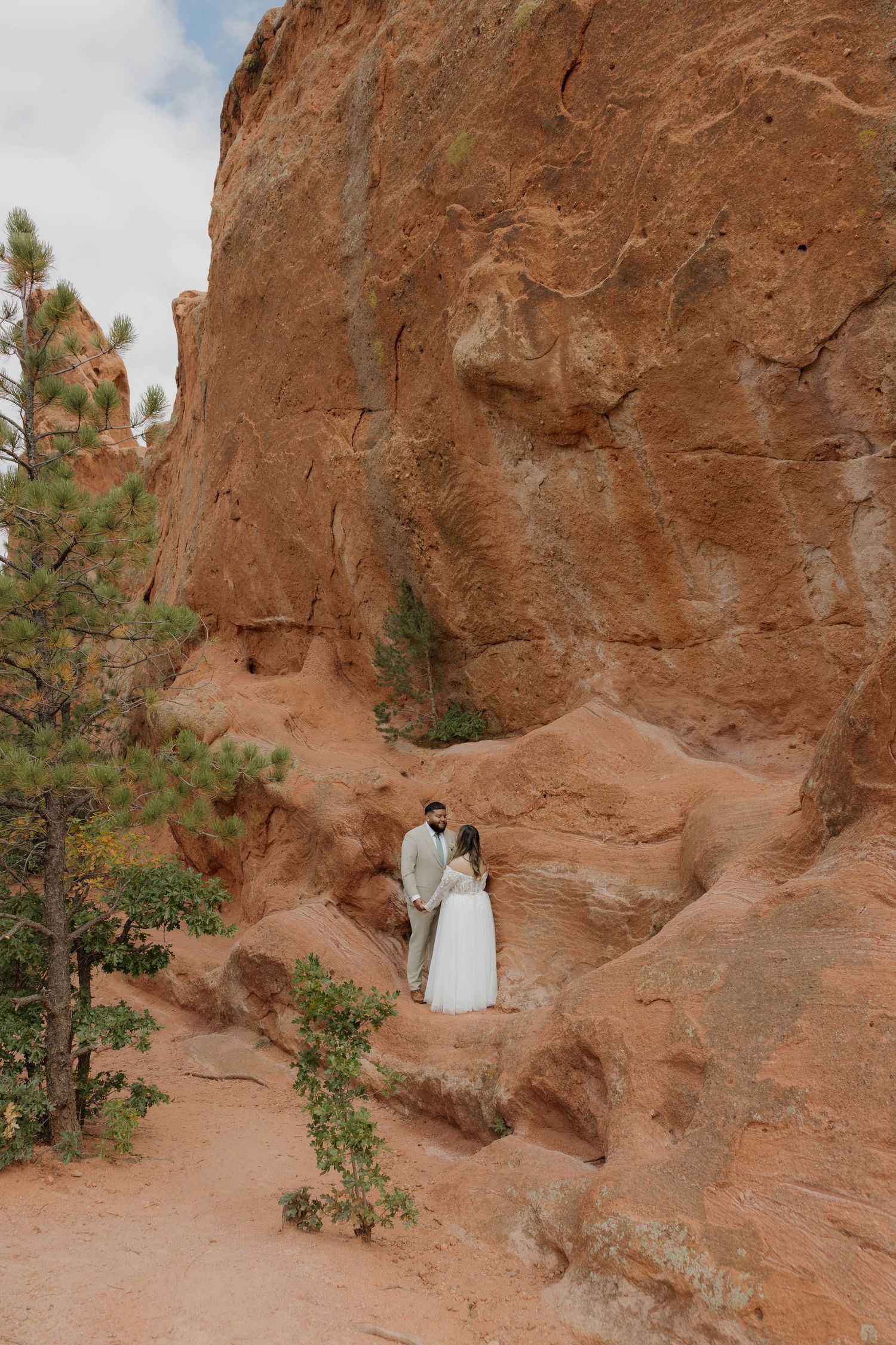 A series of five photos showing a small white statue nestled in the red rock formations of a desert landscape.