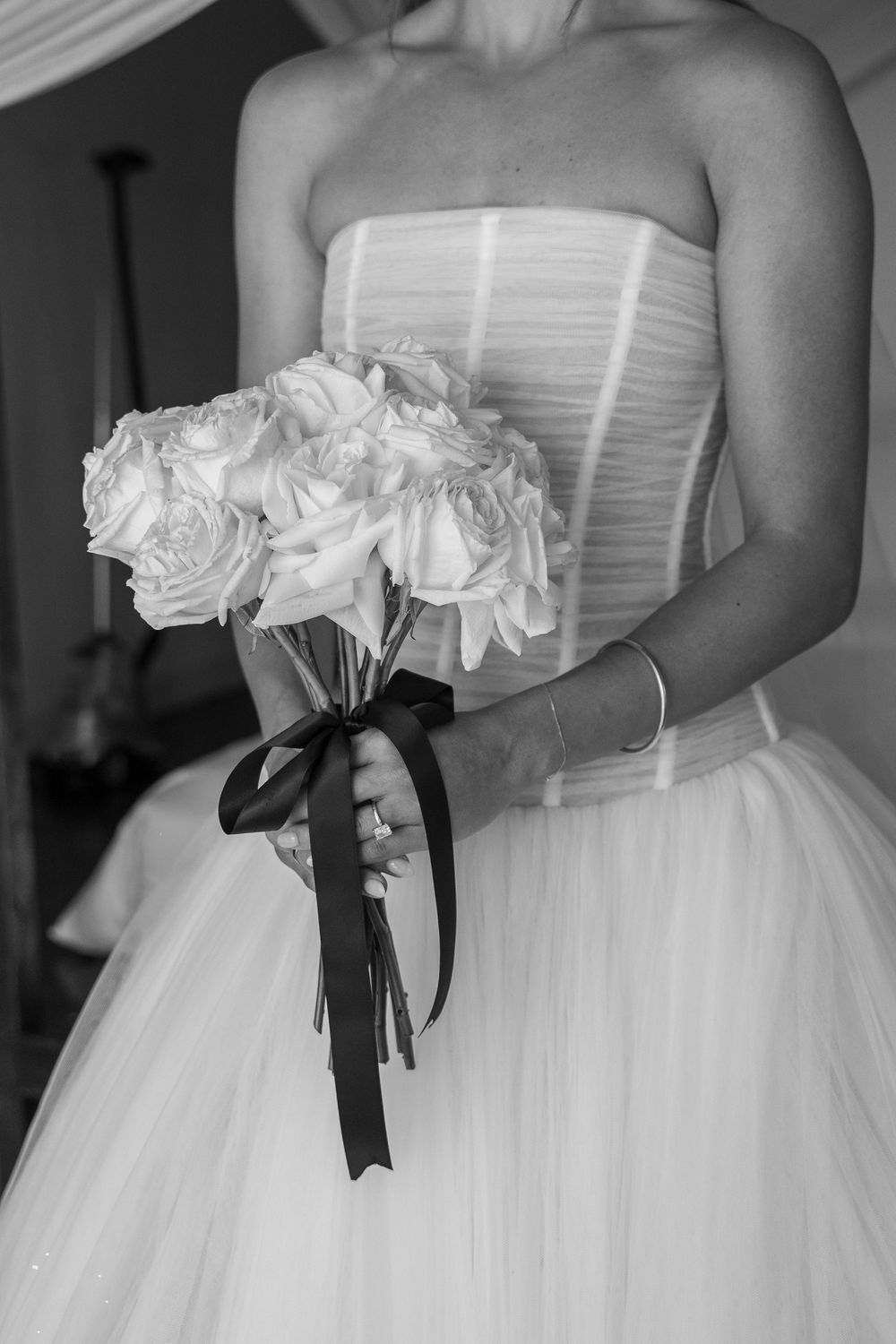 Black and white photos showing elegant white wedding dresses with floral details and black ribbon accents.