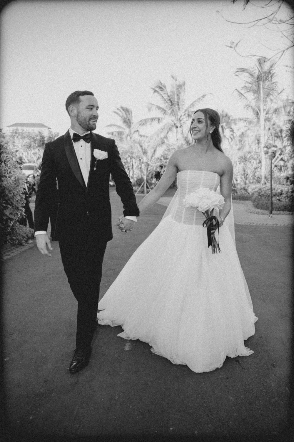 Black and white wedding photos show a couple walking together on grass in formal attire.