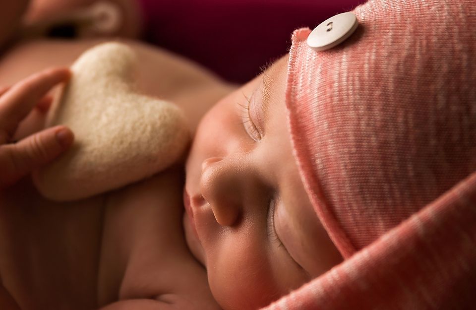 A close-up series of newborn baby features including tiny fingers, nose, and ear details in warm lighting.