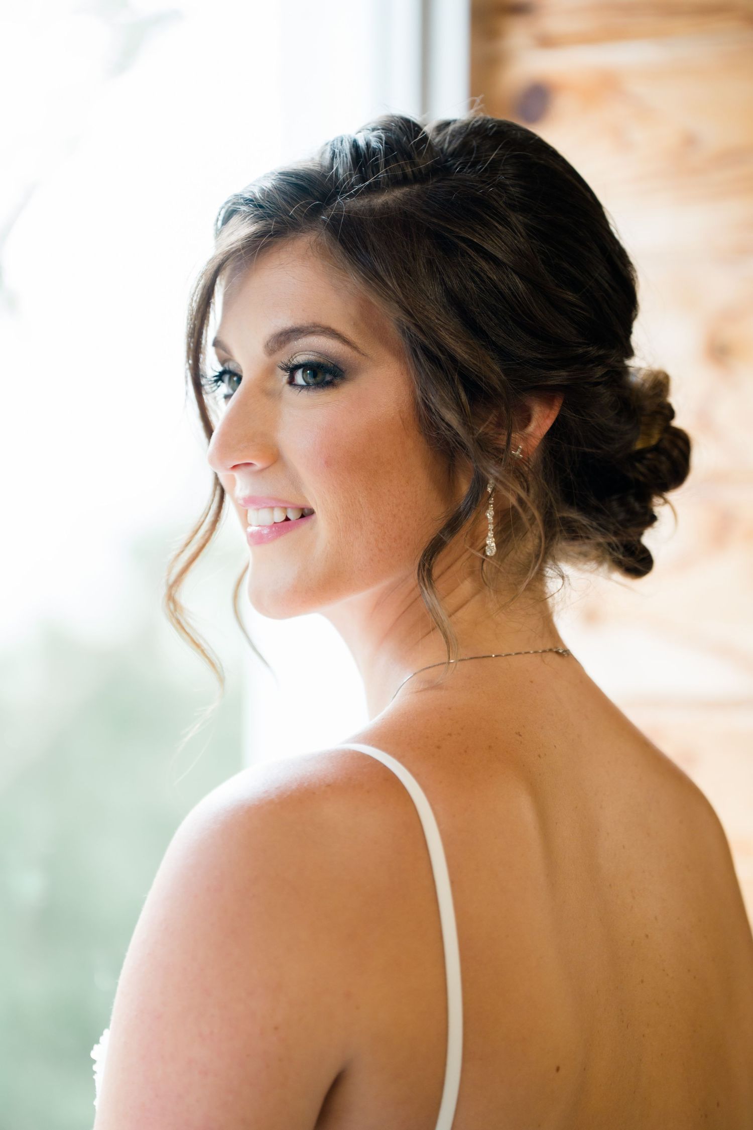 Close-up portraits of a bride with elegant updo hairstyle and makeup in natural window light.