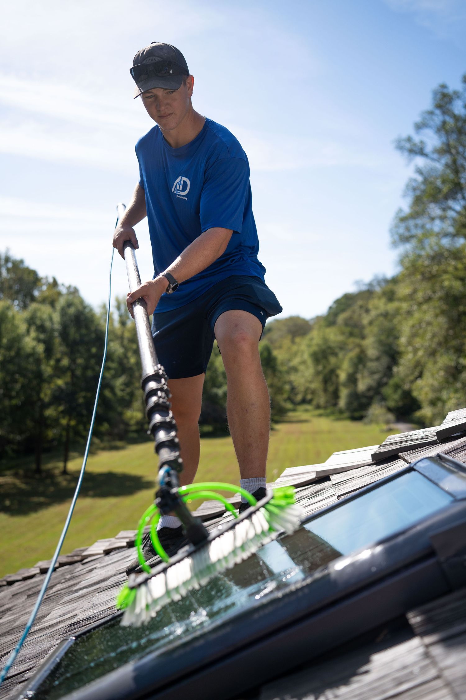 Window cleaner using professional equipment while balanced on a roof.