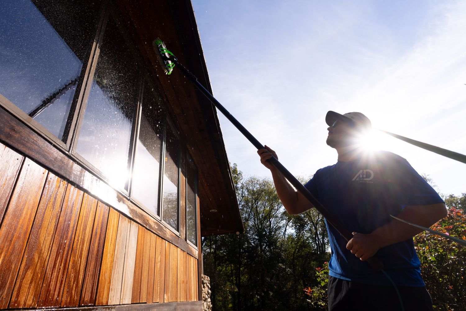 Silhouettes of window cleaners working against bright sunlight on wooden building exterior.