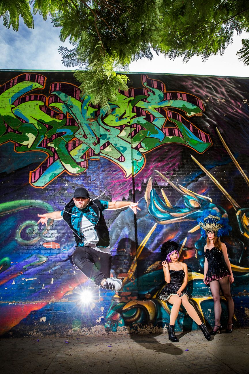 Los Angeles Brand Photographer. Urban dancers pose dramatically against vibrant graffiti wall featuring colorful artwork