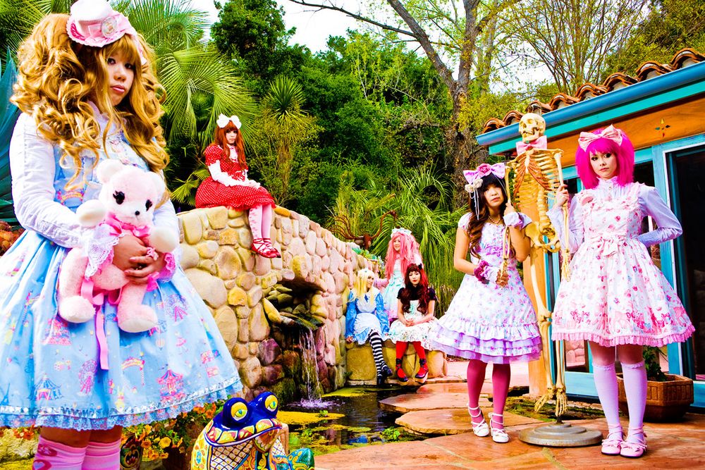 Los Angeles Brand Photographer. Group wearing pastel Lolita fashion dresses posing in a garden setting with trees and buildings.