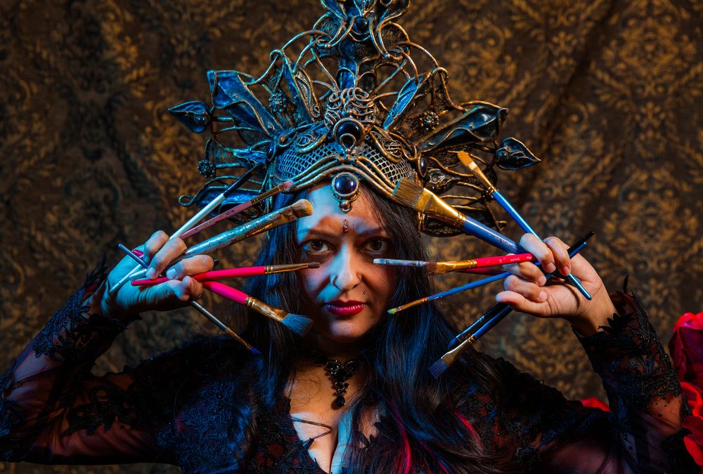 Los Angeles Brand Photographer. Woman with an elegant headpiece holding paint brushes in between her fingers and a damask backdrop.