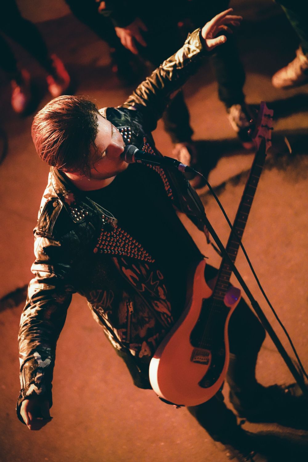 A sequence of five photos showing a rock musician performing with dramatic lighting and energetic stage presence.