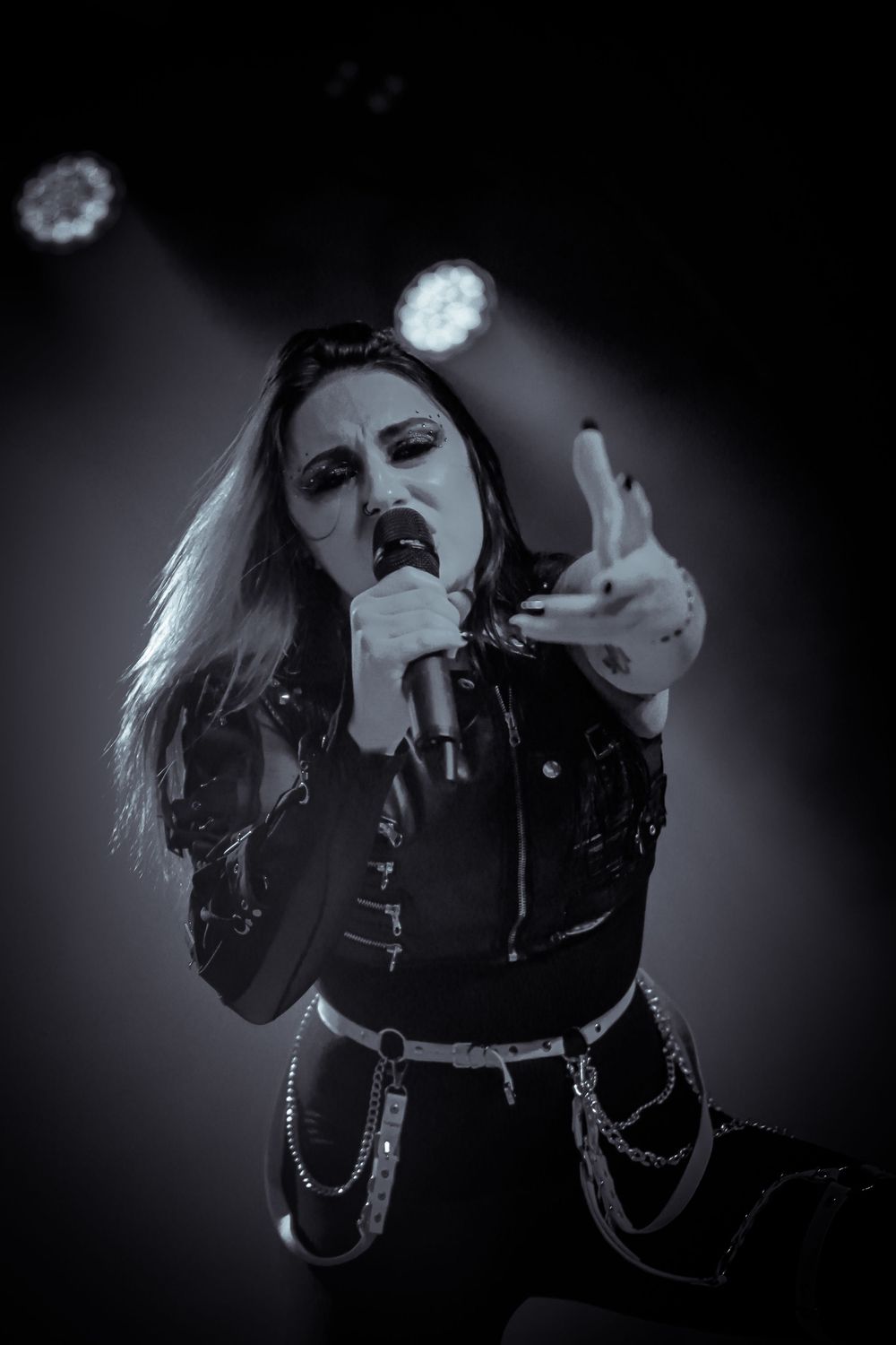 A dramatic black and white sequence shows a performer singing passionately on stage with expressive hand gestures.