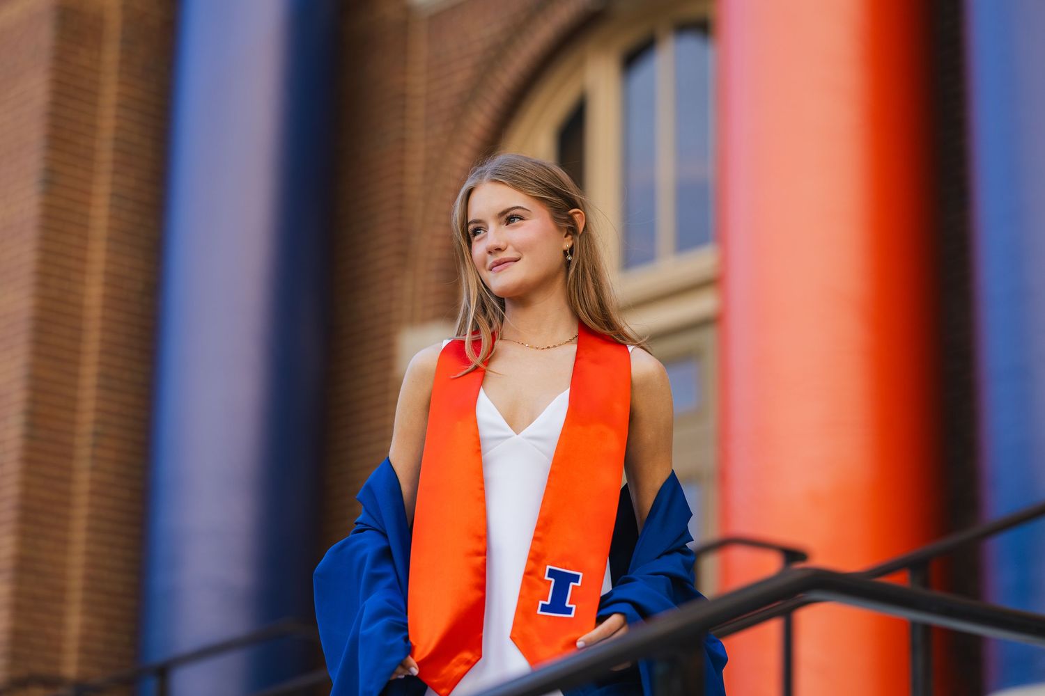 UIUC graduating student posing with her University of Illinois stole at the Foellinger Auditorium columns