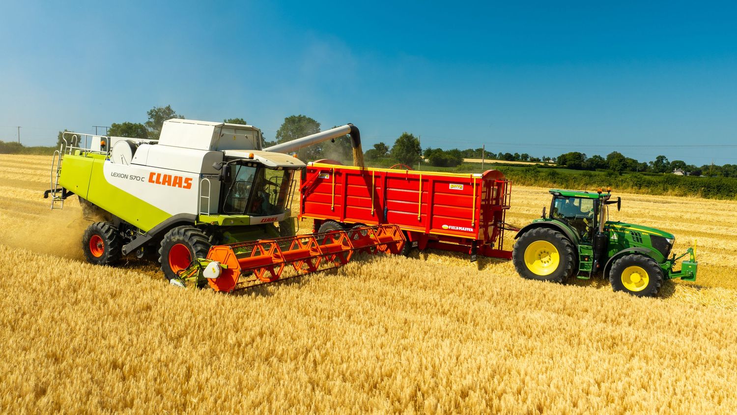 CLAAS combine harvester unloading wheat grain into a red trailer pulled by a green John Deere tractor in a sunny field.