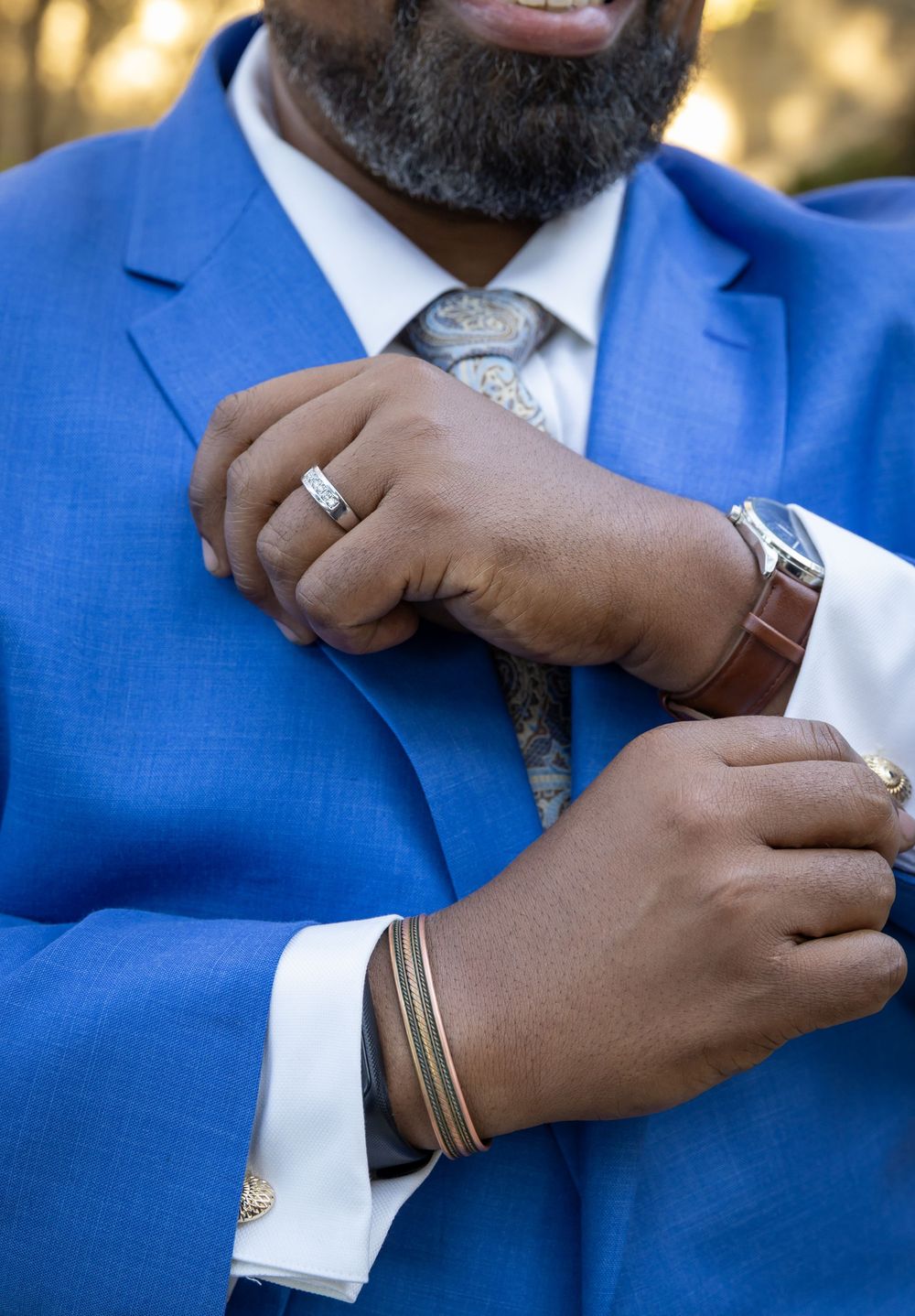 Close-up sequence of hands adjusting a white shirt cuff with cufflinks while wearing a bright blue suit jacket.